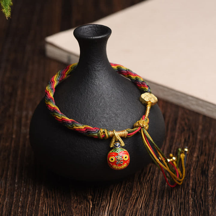 Rotes Armband mit Goldverschlingendem Wesen Familie Glück auf schwarzem Ständer.