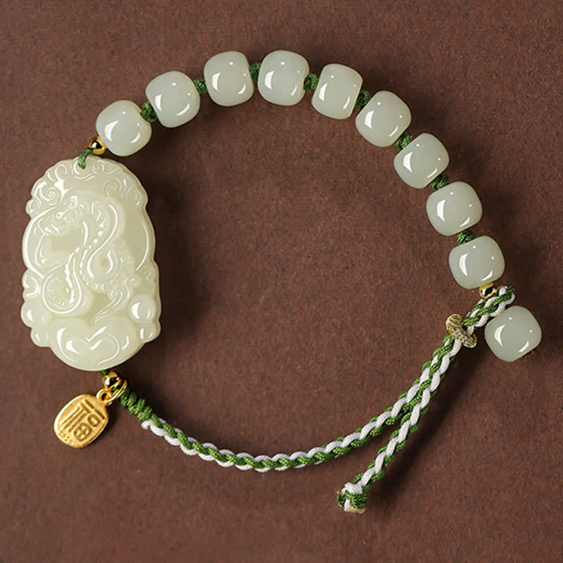 Jade Armband mit geschnitztem Anhänger und grünem Seidenband elegant.