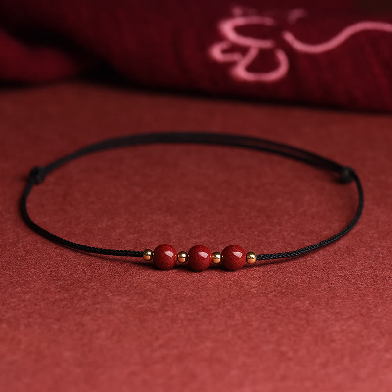 Armband Zinnober – Glück & Segen mit roten Perlen auf schwarzem Textilband