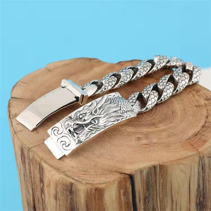 Silbernes Drachen Armband mit Kettengliedern auf Holzblock.
