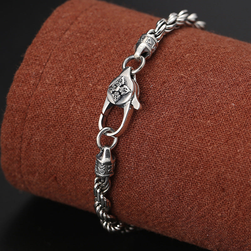 Silberarmband mit Om Mani Padme Hum Anhänger auf braunem Stoff elegant präsentiert