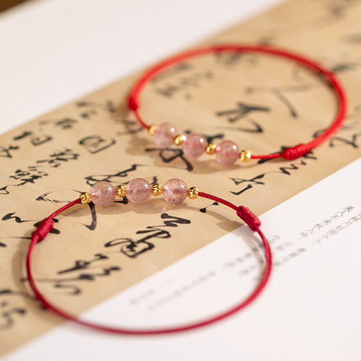 Armband Erdbeerquarz mit goldenen Perlen auf Schriftpapier Flat Lay