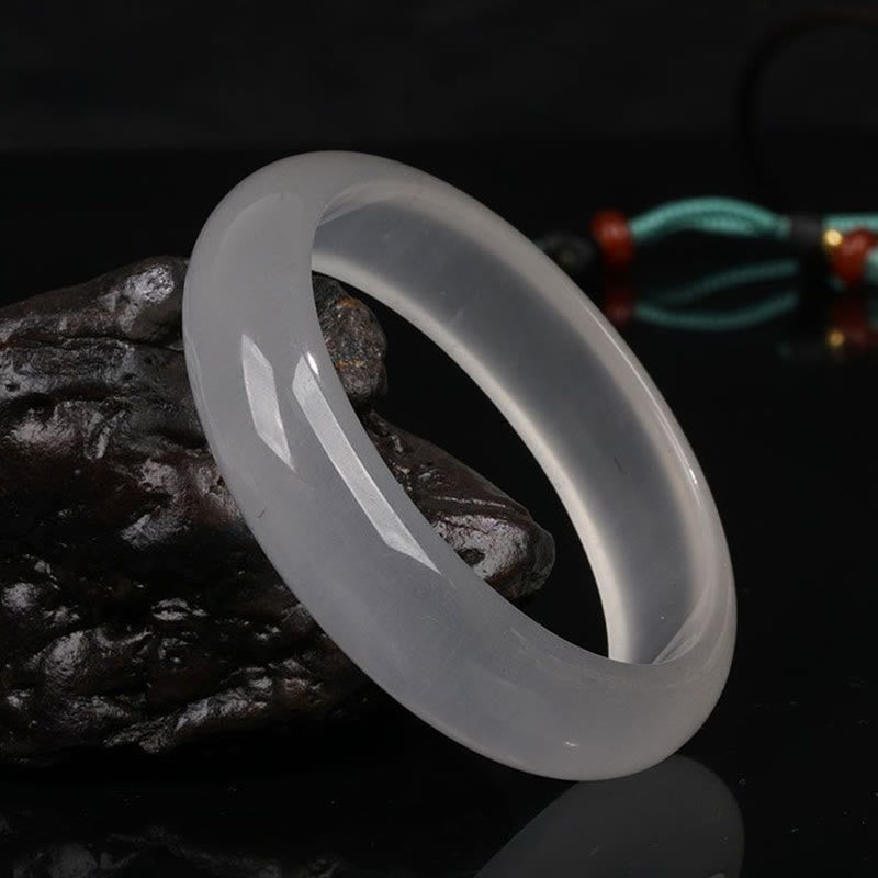 Jade Armband weiß poliert glänzend auf dunklem Stein elegante Qualität