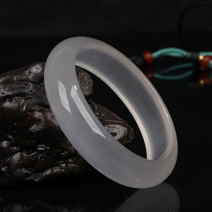 Jade Armband weiß poliert glänzend auf dunklem Stein elegante Qualität