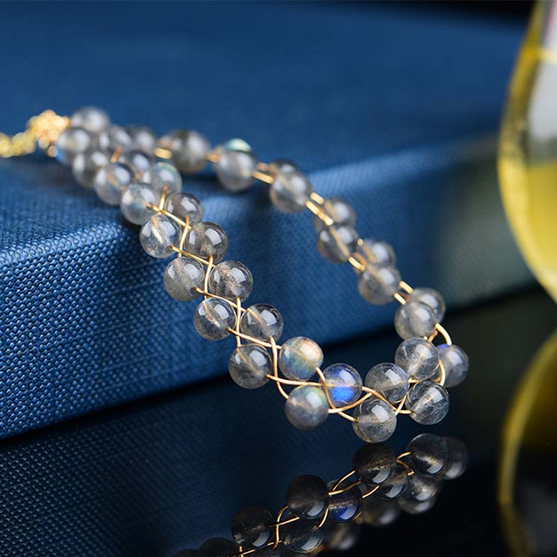 Mondstein Armband mit goldfarbenen Perlen auf blauem Stoff, elegante Nahaufnahme.