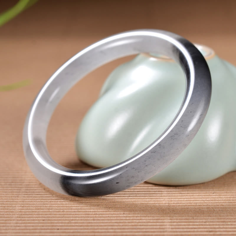 Jade Armband Wohlstand Segen grauer Stein poliert elegantes Design Holz.