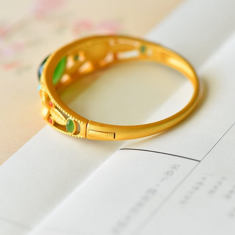 Goldenes Armband mit grüner Jade auf weißem Hintergrund elegant.