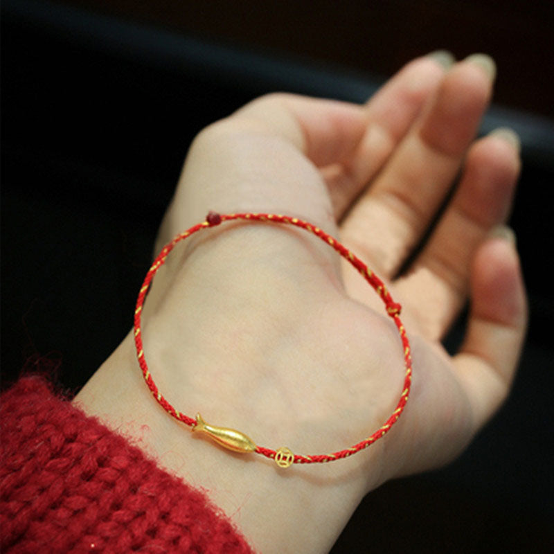 Rotes Fadenstoff Armband mit goldenem Koi Fisch Anhänger am Handgelenk