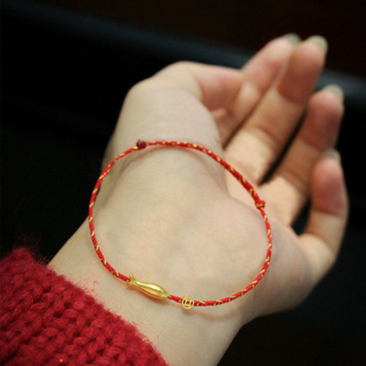 Rotes Fadenstoff Armband mit goldenem Koi Fisch Anhänger am Handgelenk