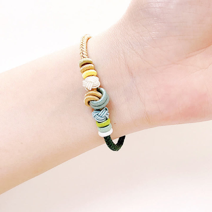 Armband – Glück & Frieden mit bunten Garnwicklungen am Handgelenk getragen