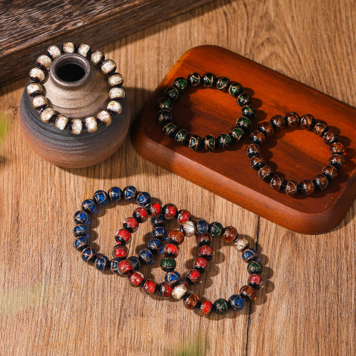 Bunte Armbänder aus Natursteinen auf Holzoberfläche angeordnet.