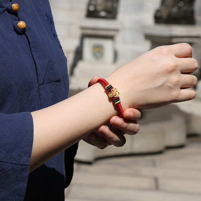 Rotes Armband mit Tierkreis-Charm am Handgelenk getragen, elastisch.