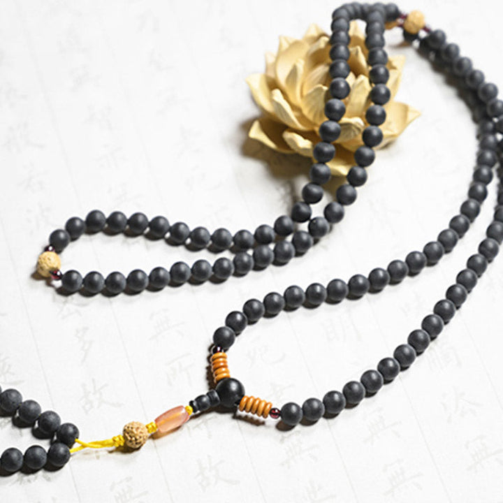 Schwarze Mala Kette mit goldenen Elementen Flachlage Bodhi Samen Anhänger