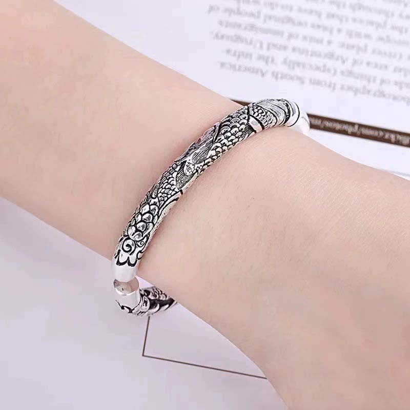 Silbernes Drachen-Armband am Handgelenk mit ornamentalen Mustern getragen