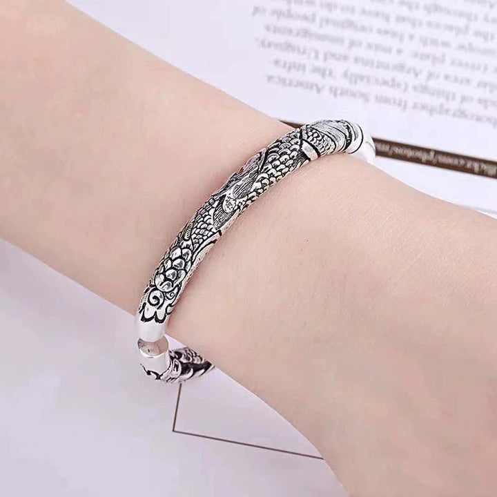 Silbernes Drachen-Armband am Handgelenk mit ornamentalen Mustern getragen