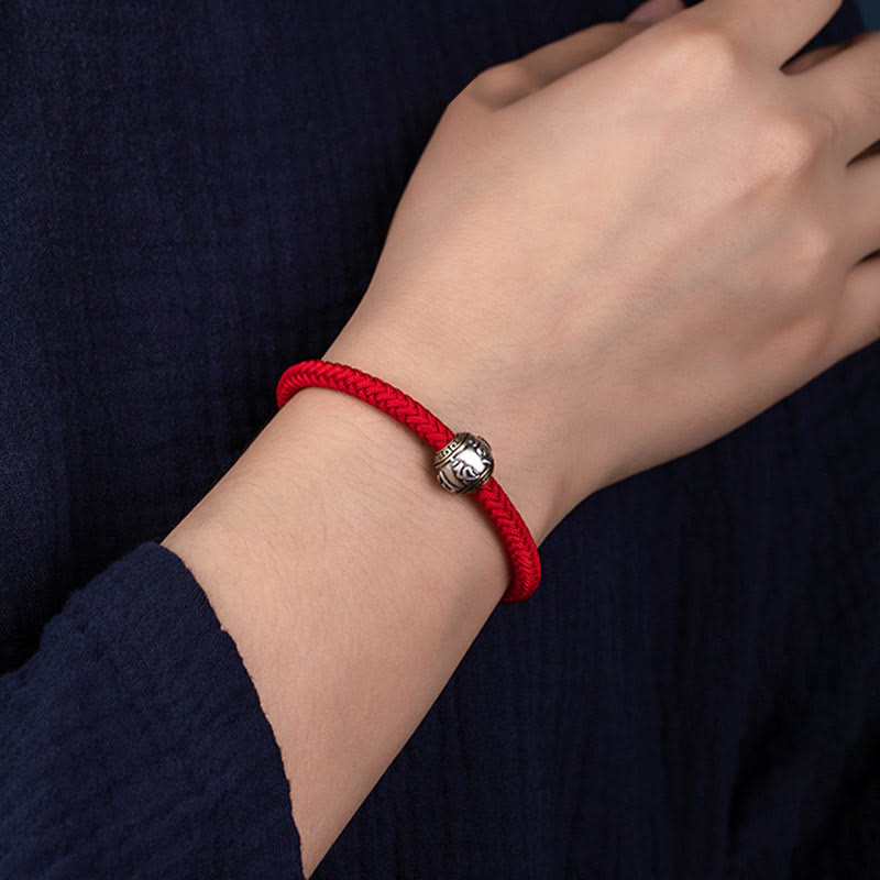 Rotes Seidenseil Armband mit silbernem Om Mani Padme Hum Charm elegant getragen