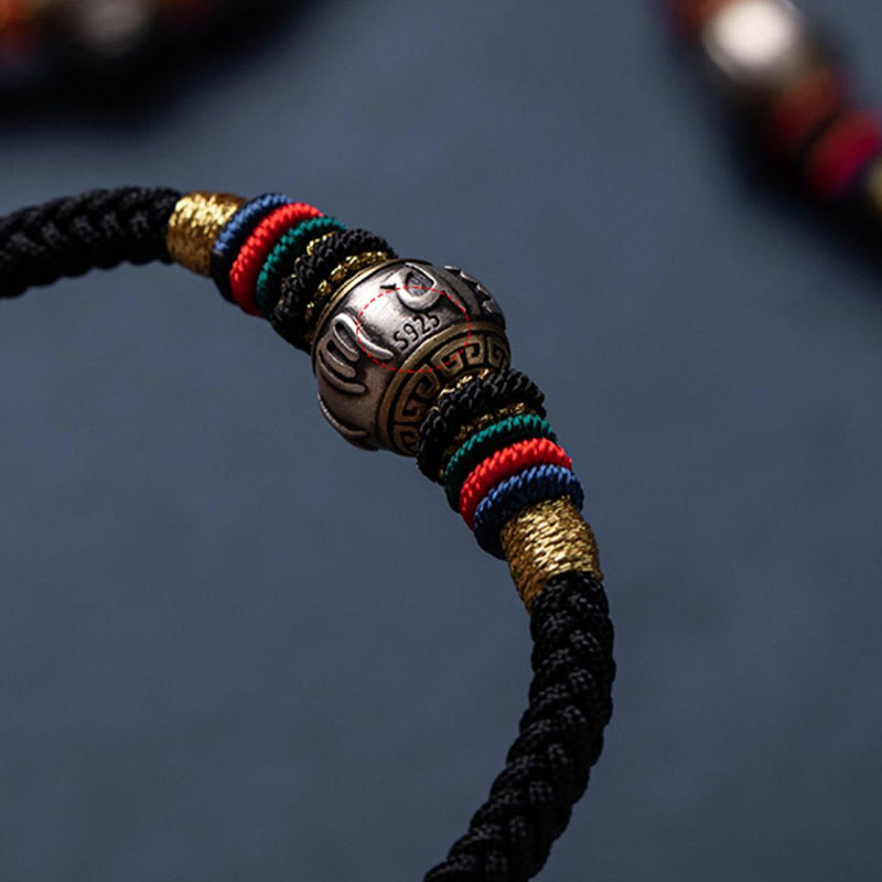 Tibetisches Armband mit Om-Perle, farbigen Bändern und Silber-Details.