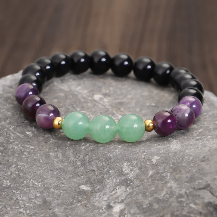 Armband mit Grüner Aventurin und Amethyst auf Stein Oberfläche.