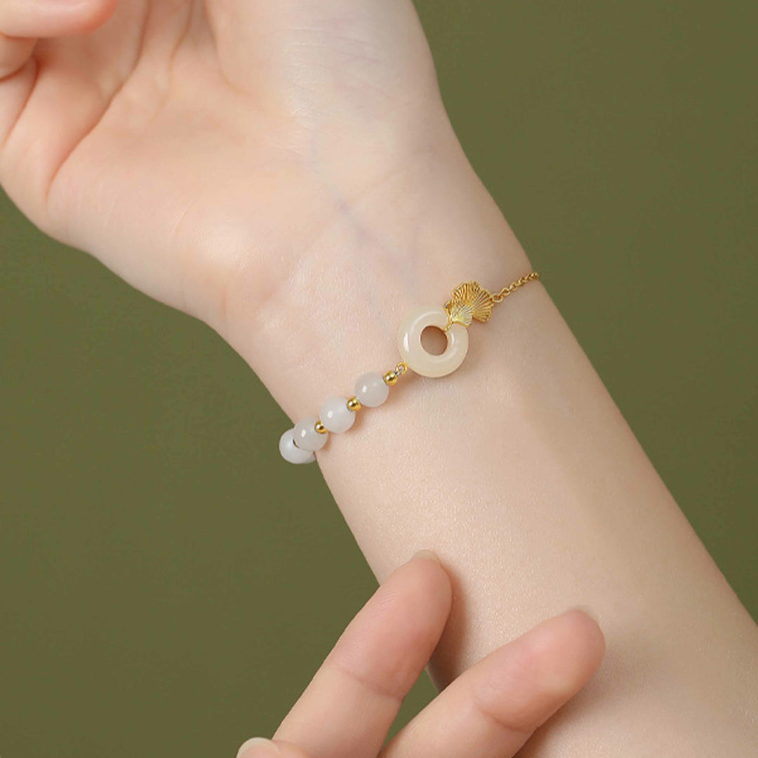 Weißes Jade Armband mit Glücksbringer elegant am Handgelenk getragen