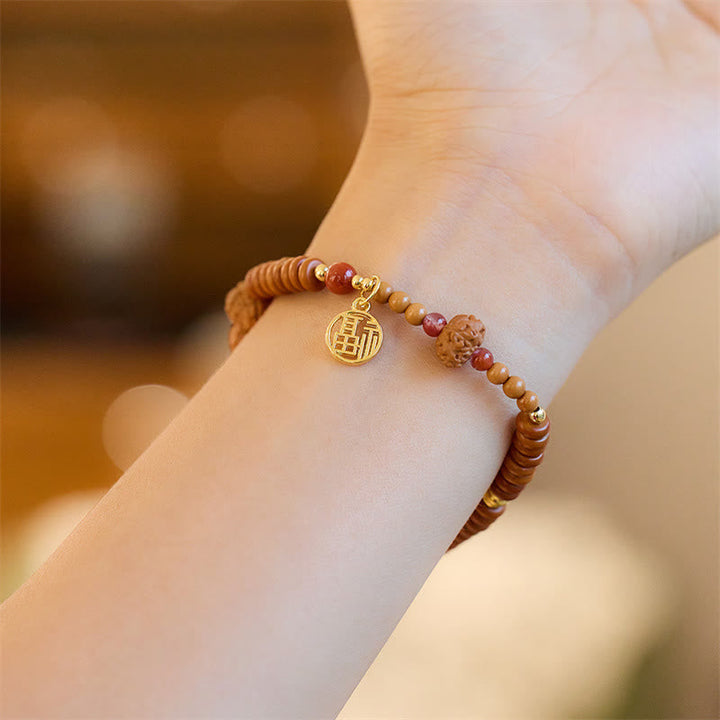 Holzperlen Armband mit goldener Om-Münze am Handgelenk getragen