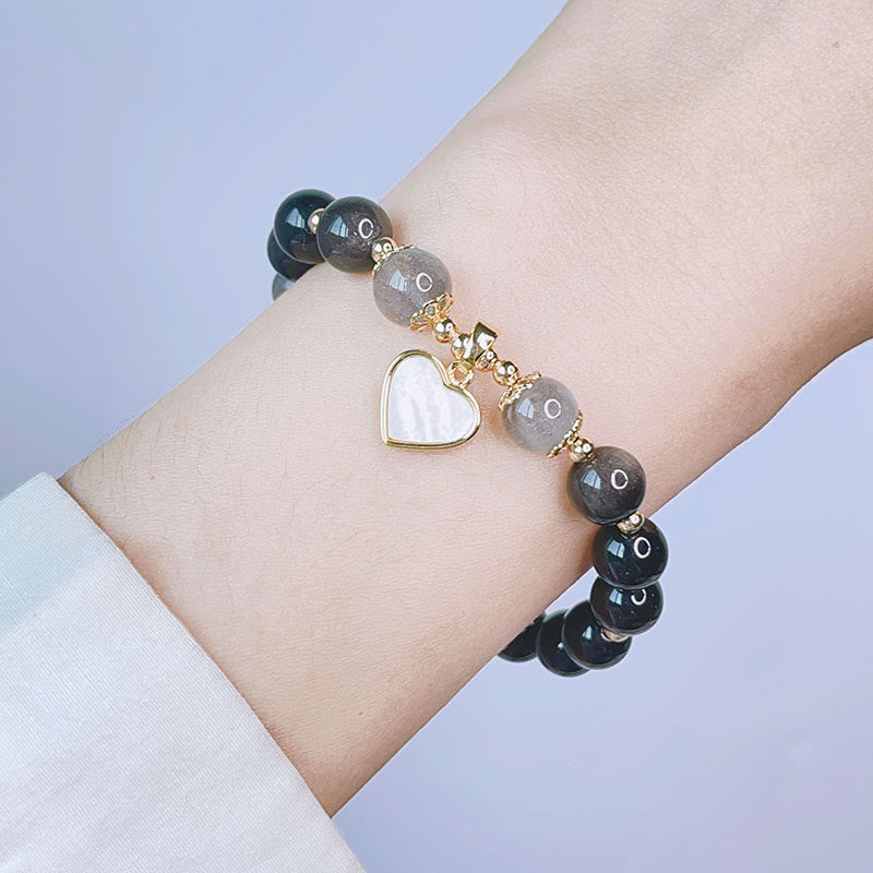 Schwarzes Obsidian Armband mit silbernem Herz Anhänger am Handgelenk getragen