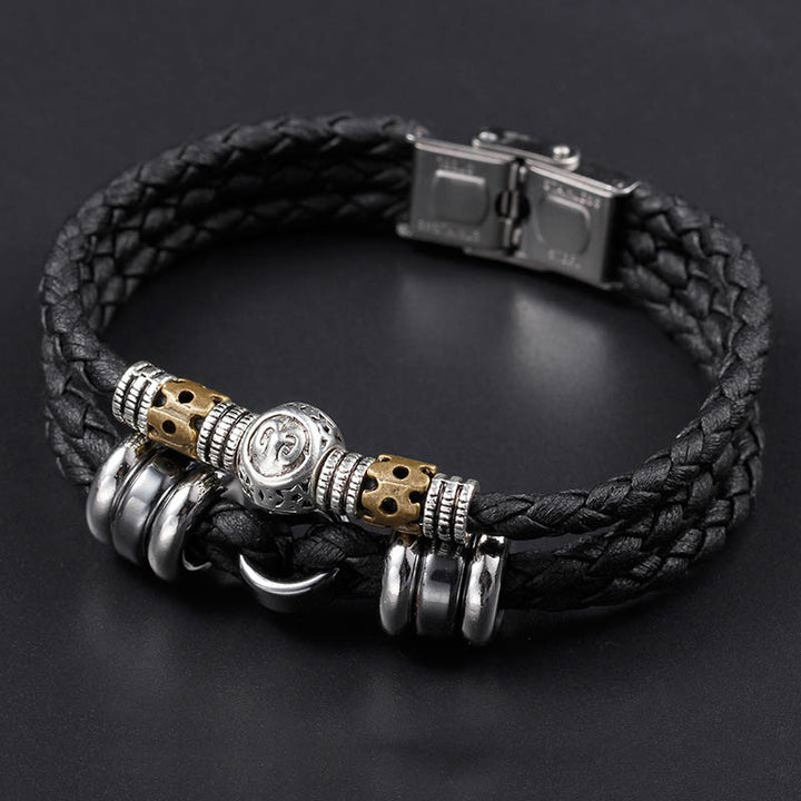 Schwarzes Lederarmband mit Hämatit Tierkreiszeichen Charm auf grauem Hintergrund
