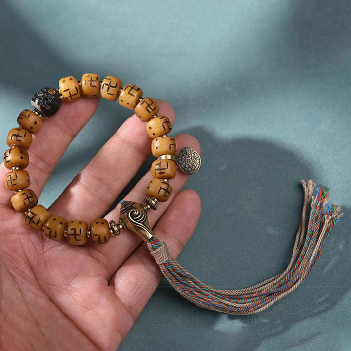 Kamelknochen Armband mit Swastika Motiv am Handgelenk mit Quasten getragen