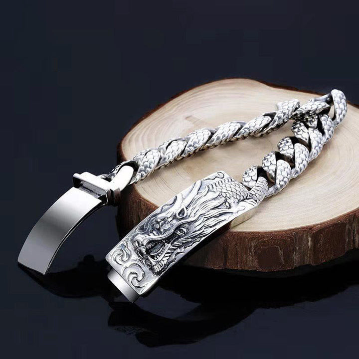 Silbernes Drachen Armband mit Kettenmuster auf Holzoberfläche displayiert.