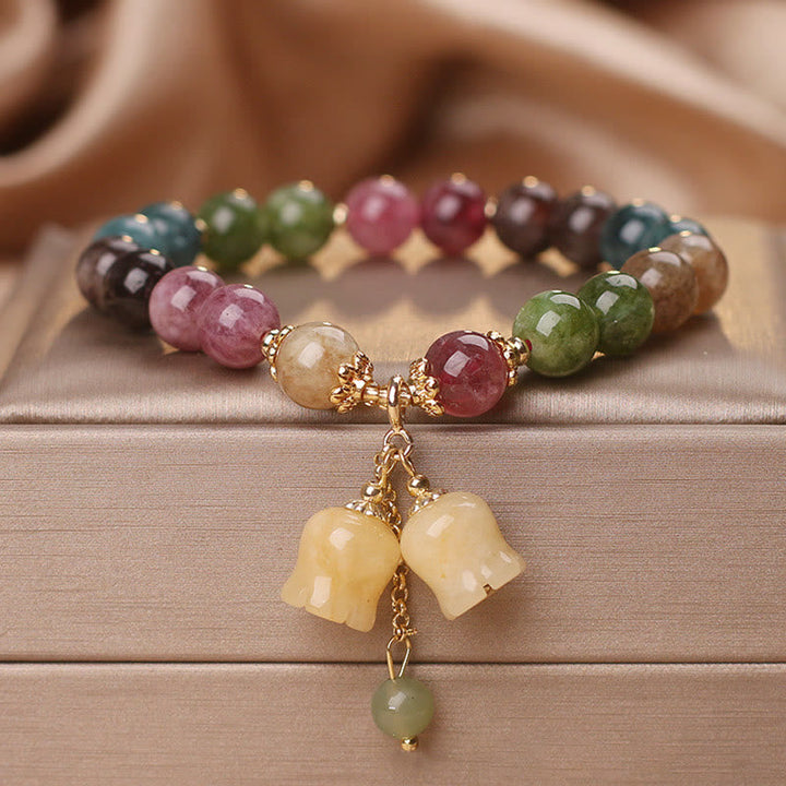 Buntes Turmalin Armband mit Blumen Anhänger auf Holz Oberfläche