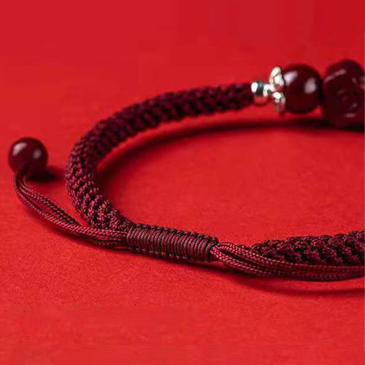 Rotes Armband Zinnober Pixiu mit Perlen auf rotem Hintergrund Nahaufnahme