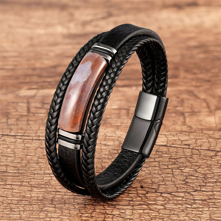 Schwarzes Leder Armband mit Roter Achat Stein auf Holz Oberfläche.