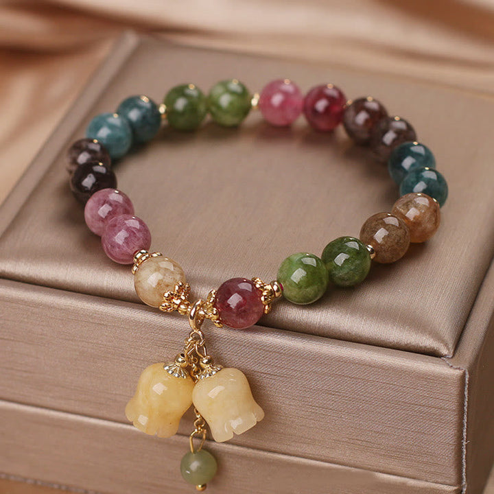 Buntes Turmalin Armband mit Blumen-Anhänger auf Holzbox elegant.
