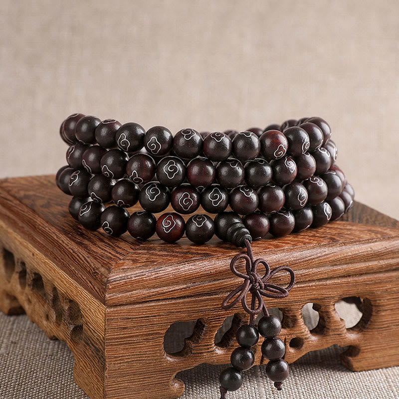 Sandelholz Perlen Armband mit Om Symbol auf Holzständer.
