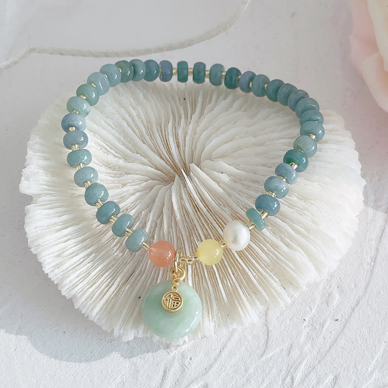 Armband Erdbeerquarz Perle Fu-Zeichen auf weißem Muschelhintergrund.