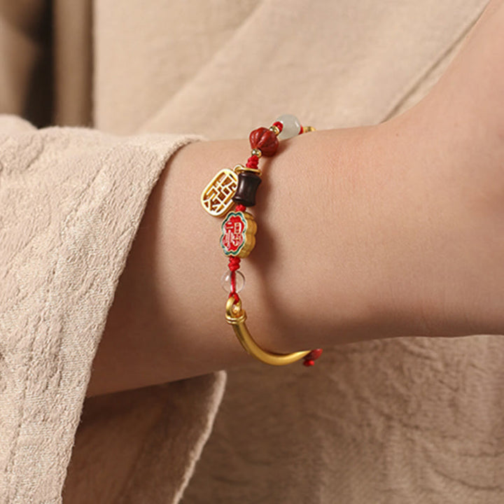 Auspicious Armband mit roten Perlen und goldenen Charms am Handgelenk
