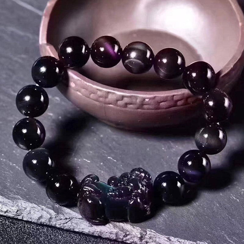 Schwarzes Obsidian Pixiu Armband mit glänzenden Perlen auf Stein