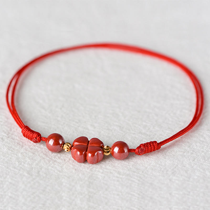 Rotes Armband Zinnober Kleeblatt mit goldenen Perlen auf weißem Hintergrund elastisch