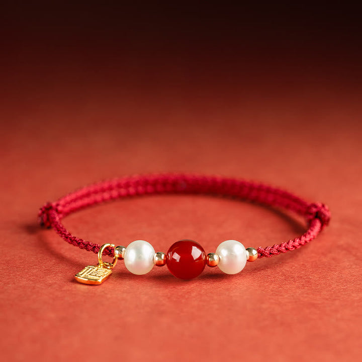 Rotes Armband mit Perlen und Achat auf korallenfarbenem Hintergrund elegant.