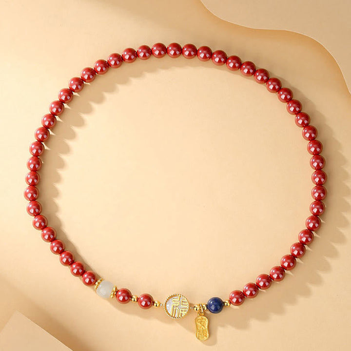 Rotes Perlenarmband mit goldenen Akzenten und Anhängern elegant präsentiert.