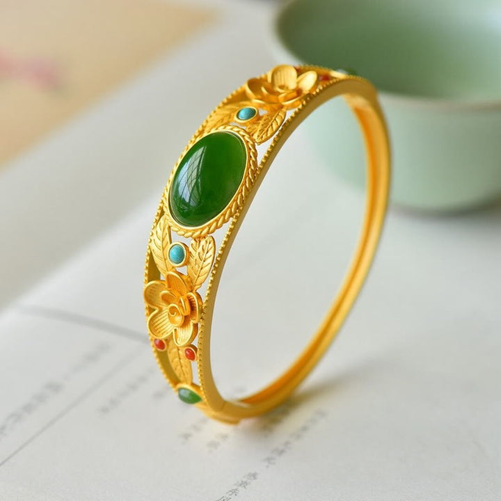 Goldenes Armband mit grüner Jade und türkisen Steinen, elegantes Design.