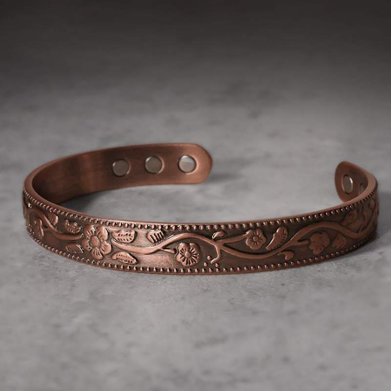 Kupfer Armband mit graviertem Blumenmuster auf Marmor Oberfläche.