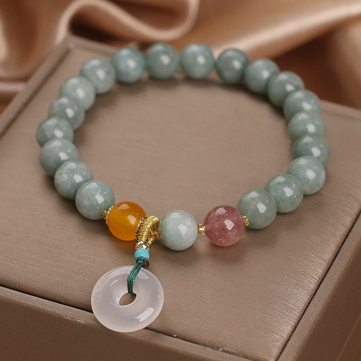 Armband Erdbeerquarz Jade mit Anhänger auf beiger Oberfläche.
