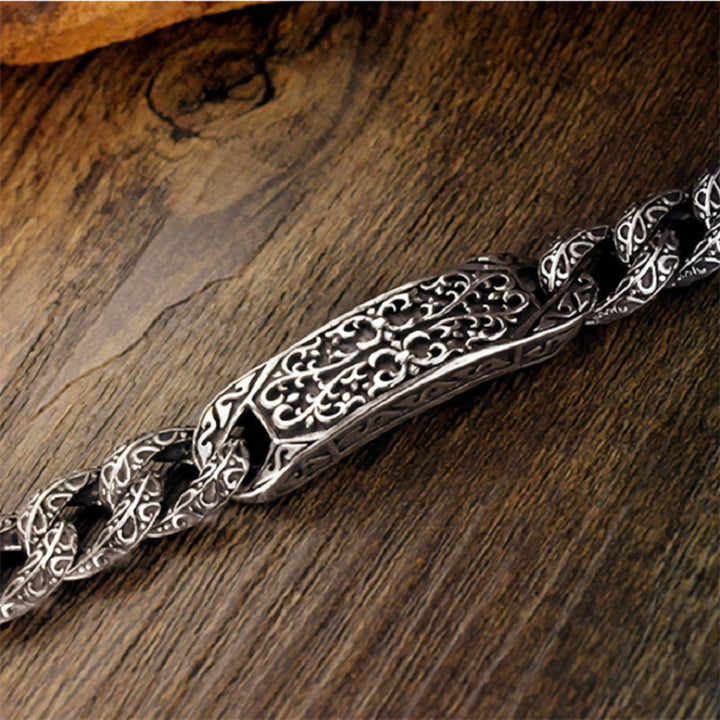 Silbernes Armband mit ornamentaler Gravur auf Holzoberfläche liegend.