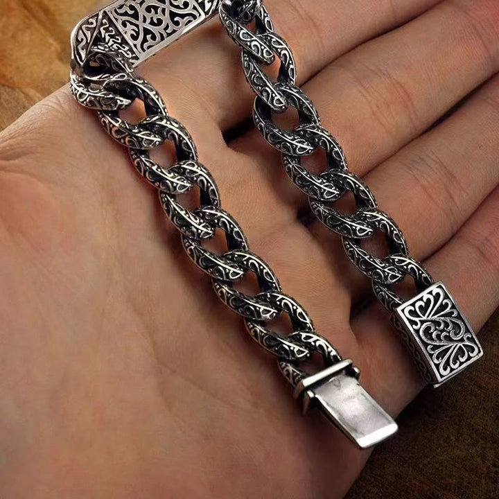 Silbernes Armband mit ornamentalem Kettenglied-Design am Handgelenk.