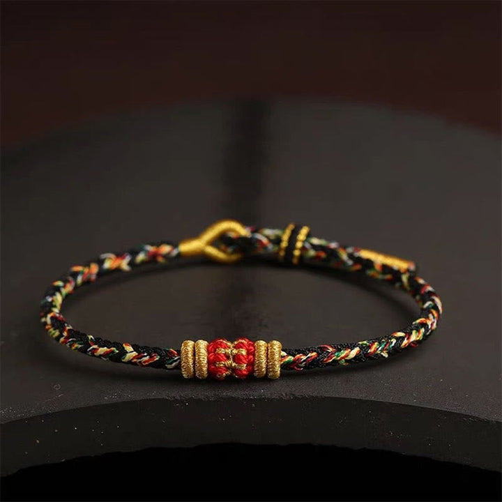 Armband bunt geflochten Knoten Glück goldene Perlen schwarzer Hintergrund