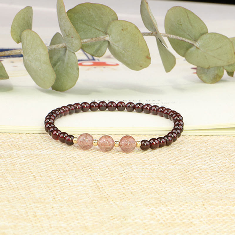Armband Erdbeerquarz Granat auf heller Leinenfläche mit Eukalyptus.