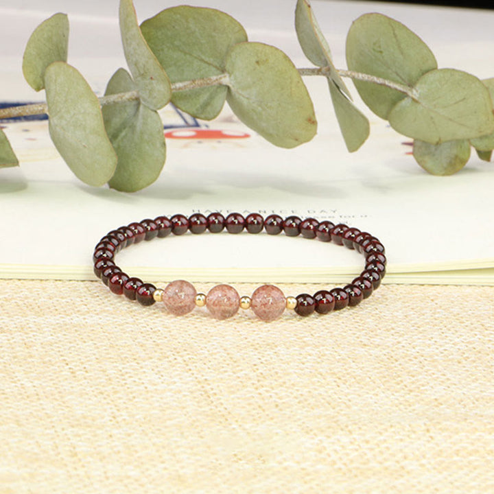 Armband Erdbeerquarz Granat auf heller Leinenfläche mit Eukalyptus.