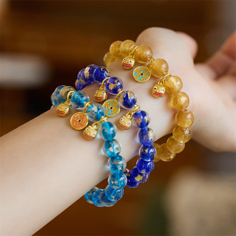 Drei bunte Armbänder mit Perlen und Glücksbringern am Handgelenk getragen.