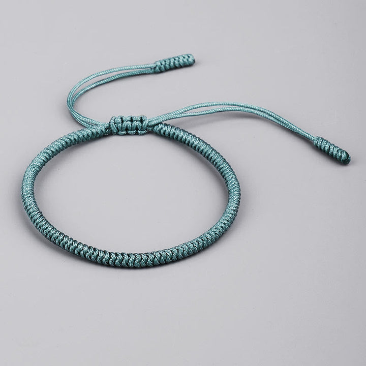 Tibetisches geflochtenes Armband mit Knoten in Türkis auf grauem Hintergrund