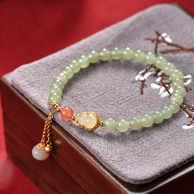 Jade Armband mit goldenem Lotus Anhänger auf grauem Kissen elegant